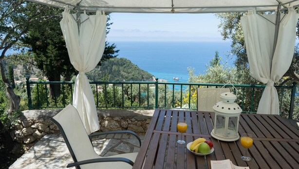 Une table avec vue sur la mer, une lanterne et un menu.