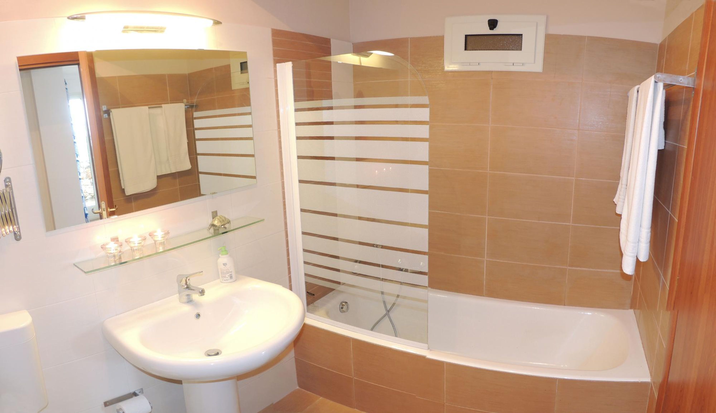 A bathroom with a glass-enclosed shower, a white sink, and a mirror above the sink.
