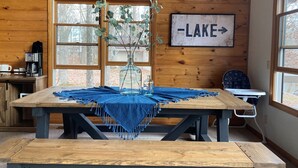 Un intérieur rustique en bois, avec une grande table, une machine à café et une pancarte sur laquelle on peut lire « LAC ».