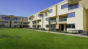 A modern apartment building with multiple balconies, a well-maintained lawn, and a clear sky. - Katya Resort A3 9 by Wonderful Italy (Desenzano del Garda)