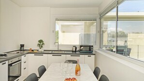 A modern kitchen with a dining area, large windows, and a view of the city. - Katya Resort A3 9 by Wonderful Italy (Desenzano del Garda)