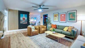 A modern living room with a sofa, two armchairs, a coffee table, and a ceiling fan. There are framed pictures on the wall and a plant on the floor. - Luxury Lakeside Adventureland! (Mesa)