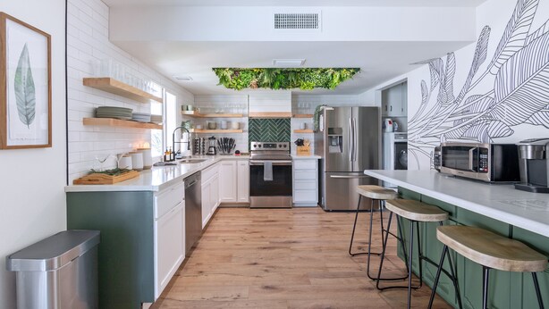 Una cocina moderna con armarios blancos, encimera de madera, estufa integrada y un microondas.