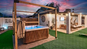Un patio trasero con jacuzzi, dardos y un porche de madera.