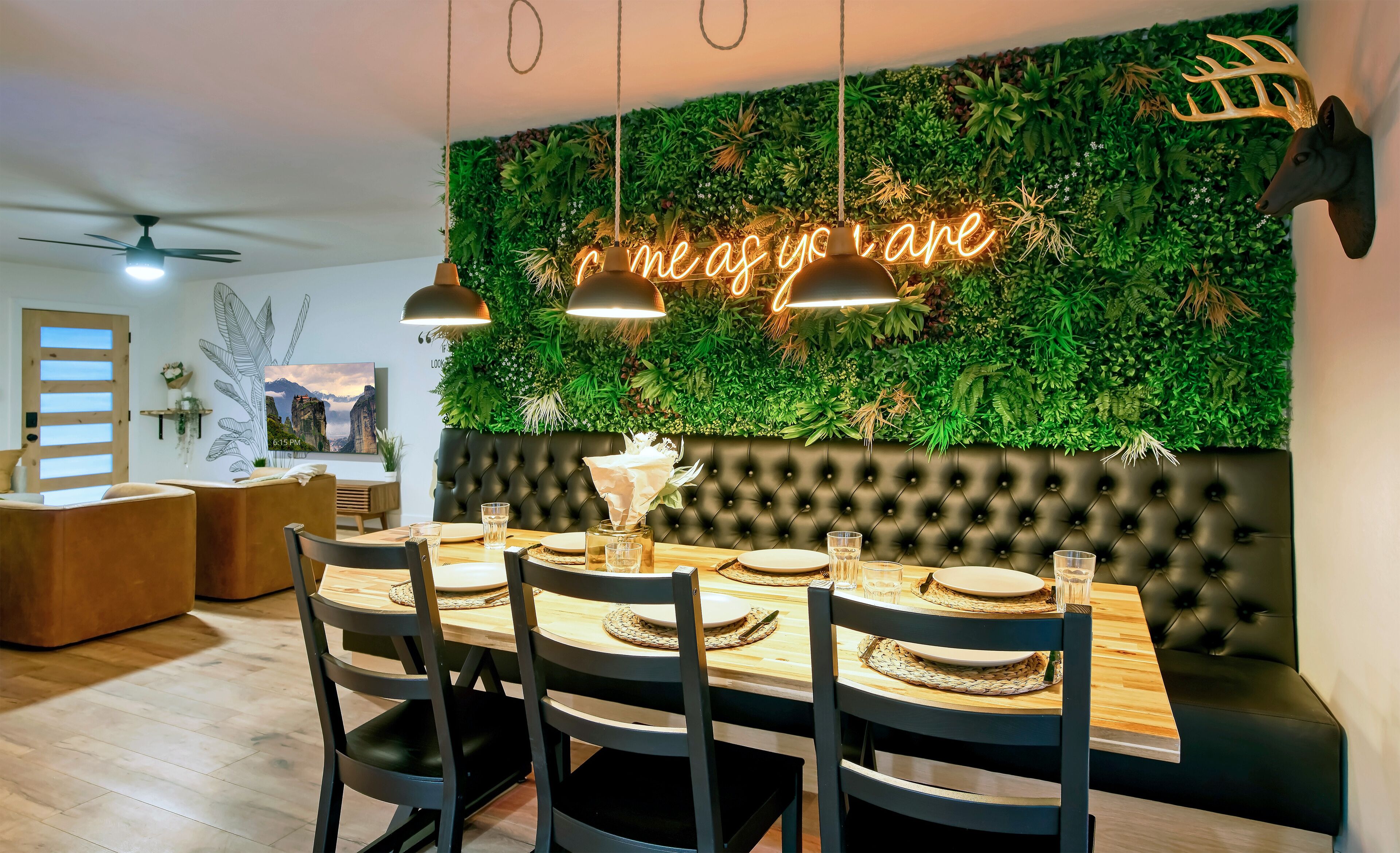 Ein moderner Essbereich mit grüner Wand, einer Neonreklame und einem geblankten Kopfteil.