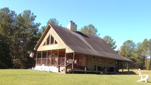 A large, single-story house with a covered porch and a fenced yard.