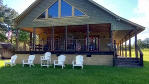 A two-story building with a covered porch and a large window. There are five Adirondack chairs aligned in front of the building.
