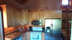 A kitchen with wooden cabinets, a stainless steel refrigerator, a microwave, and a stove.