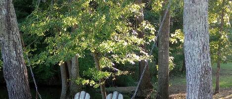 A rustic outdoor setting with a wooden swing and a metal pot.