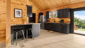 Una cocina moderna con paredes de madera, gabinetes negros y una zona de bar con dos taburetes.