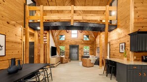 Interior espacioso de una cabaña de madera con comedor, asientos y cocina.