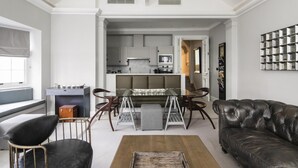 A spacious living room with a high ceiling, a dining area, and a kitchen in the background. - The Park Lane Penthouse (London)