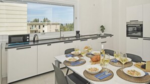 Ett modernt kök med vita skåp, en inbyggd ugn och ett matbord dukat för en måltid.