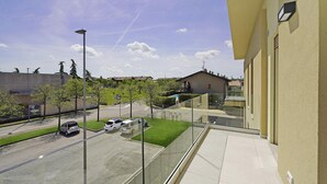 En balkong med fri utsikt över en parkeringsplats, en gräsyta och en byggnad med en beige fasad.
