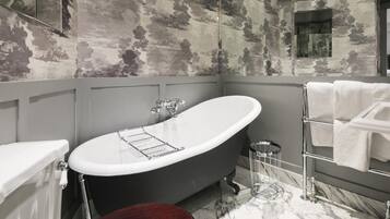A bathroom with a freestanding bathtub, a toilet, a sink, a towel rack, and a mirror.