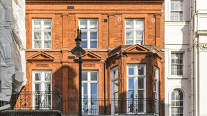 A red brick building with a classic architectural style, featuring a prominent entrance with a black door, a balcony with ornate metal railings, and a blue directional sign indicating 'Old Town' to the right. - The Hanover Suite in London (London)