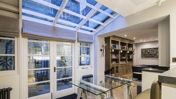 A modern interior with a glass ceiling, a glass table, and a bookshelf. - The Hanover Suite in London (London)