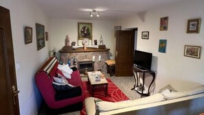 Una sala de estar con chimenea, un sofá, una televisión y una mesa de comedor.