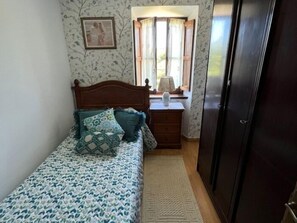 A bedroom with a bed, a nightstand, a dresser, a window with curtains, and a door. - Casa La Pereda - country house in Noriega (Ribadedeva) | 6 guests (Noriega)