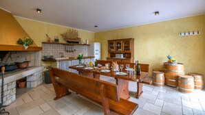 A kitchen with a central island, wooden benches, and a dining table set for four. There are wooden cabinets, a tiled backsplash, and a ship decoration on the wall. - Villa Casa Brazzana Zadarvillas (Buzet)
