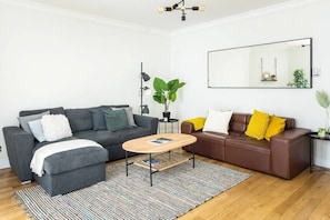 Relax in this stylish living room with two sofas, a coffee table, and a large mirror.