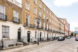 Rows of charming houses with brick facades and white window frames line the quiet street.
