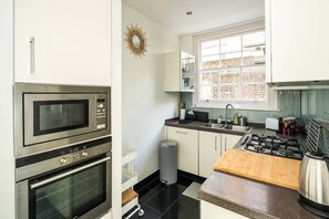 Enjoy cooking in this well-equipped kitchen with a gas stove, microwave, and oven, offering a city view.
