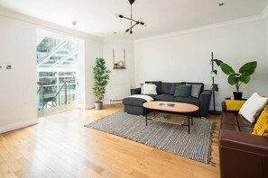 Relax in this inviting living room with a sofa, armchair, and coffee table, surrounded by natural elements and warm furnishings.