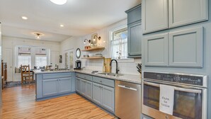 Una cocina moderna con armarios grises, piso de madera y horno de acero inoxidable.