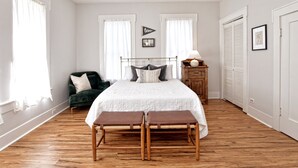Un dormitorio con cama, banco, cómoda y silla.
