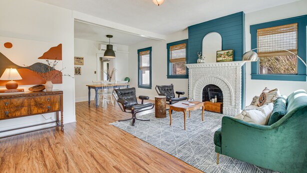 Una sala de estar con chimenea, piso de madera y sofá verde.