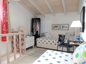A bedroom with a bed, a desk, a chair, a wardrobe, and a window with curtains.