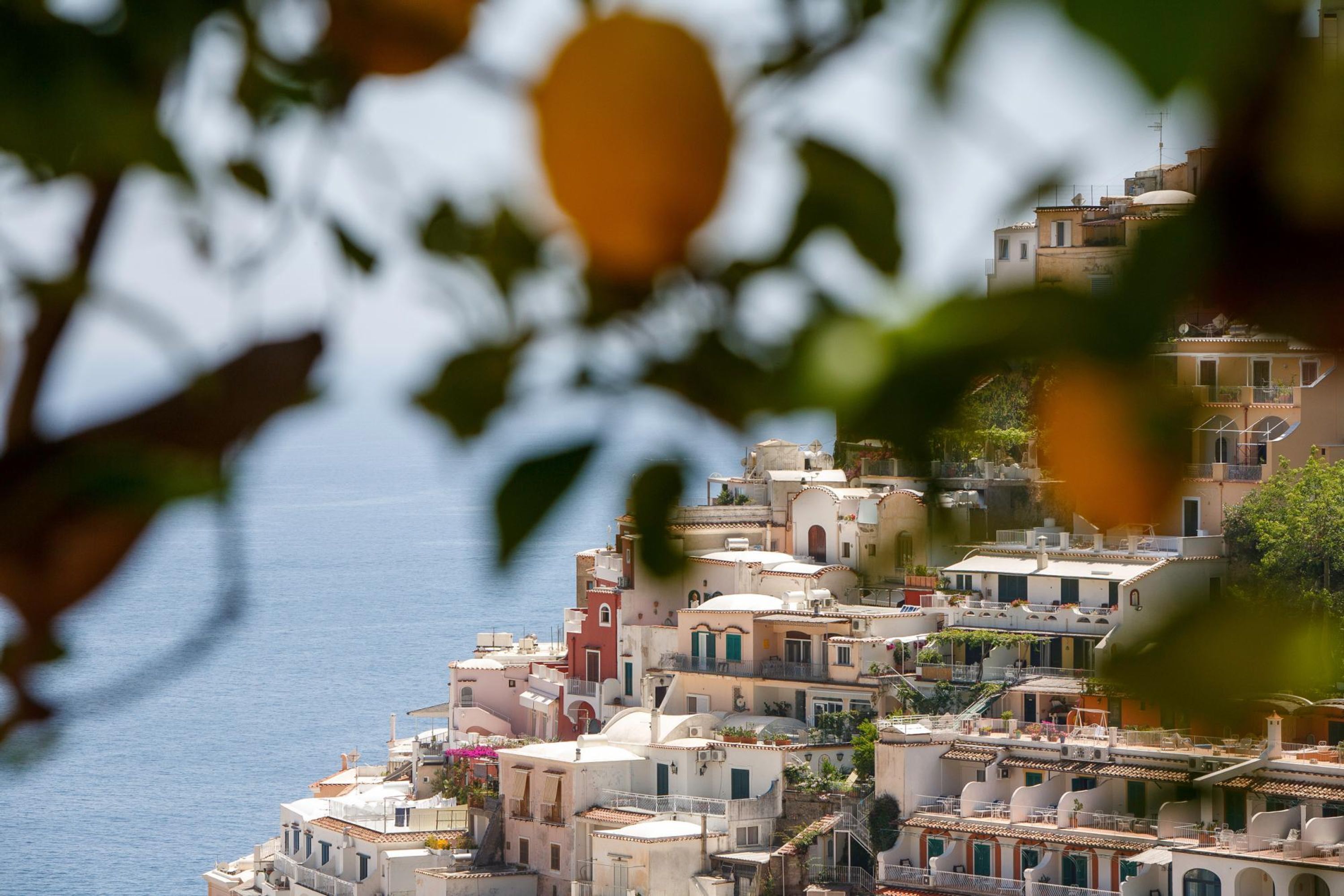 A coastal town with closely packed buildings, balconies, and a view of the sea.
