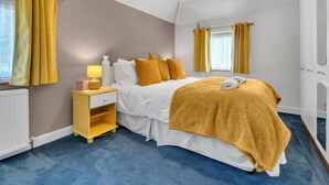 A bedroom with a bed, bedside table, lamp, and curtains. - Valley Rise By My Getaways Free Parking (Brighton)