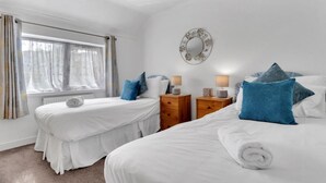 Une chambre d’hôtel avec deux lits, une grande fenêtre avec des rideaux, un miroir au mur et des lampes de chevet.
