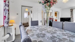 Une chambre d’hôtel comprenant un lit, un coin salon avec une table, un vase décoratif avec des fleurs, un radiateur et un téléviseur.