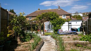 Un jardin résidentiel avec un chemin menant à une maison dont le toit est recouvert de tuiles.