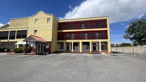 A two-story building with a yellow facade and a red balcony. - St. Lawrence Suites - Suite Two (Oistins)