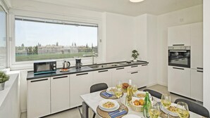 Eine moderne Küche mit weißen Schränken, einem großen Fenster und einem Essbereich, der für eine Mahlzeit gedeckt ist.