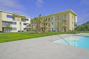 Um edifício de apartamentos moderno com piscina, varandas e um gramado bem cuidado.