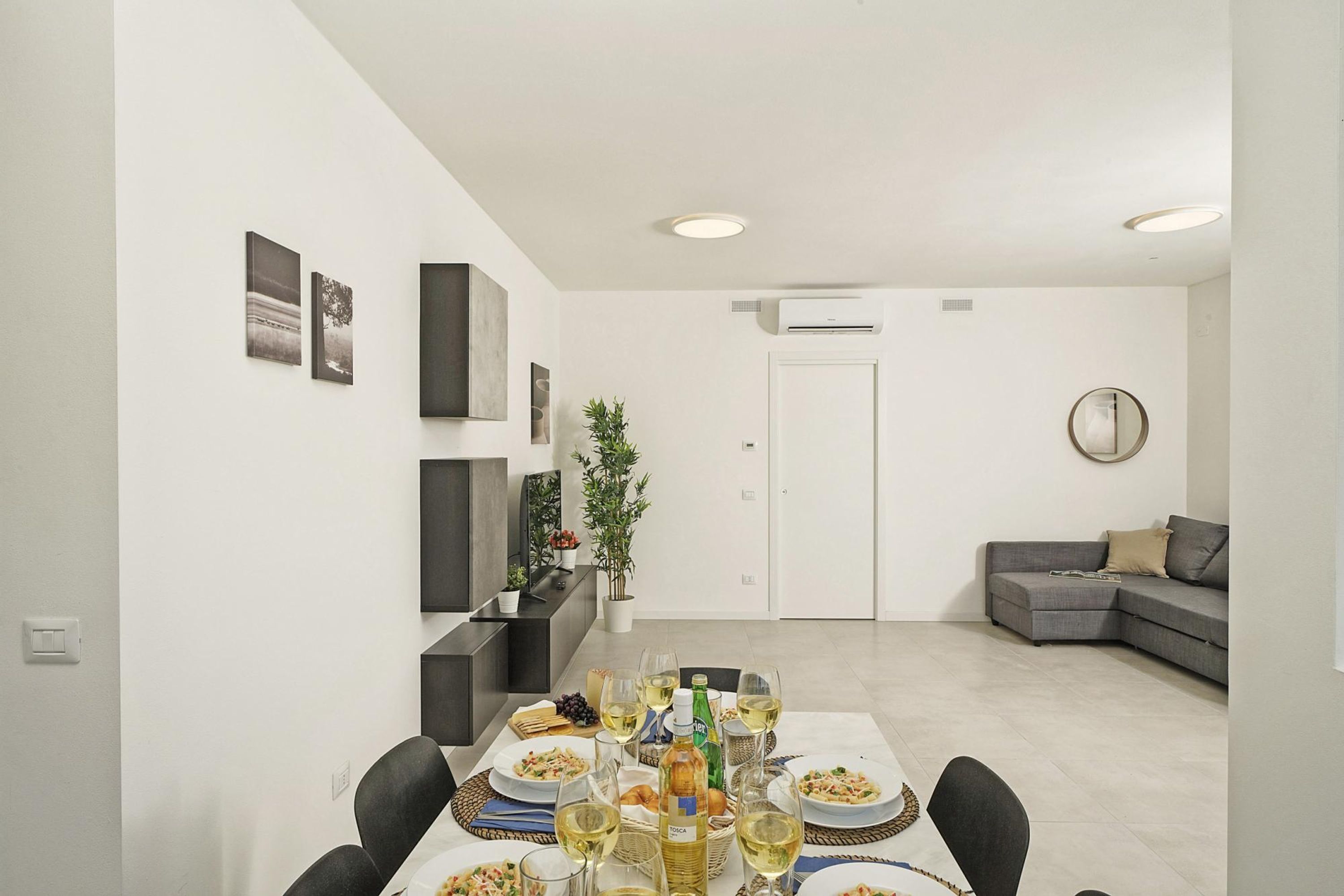 A dining area with a table set for a meal, a grey sofa, and a white door in the background.