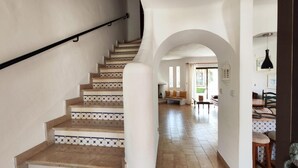 Un escalier orné de carreaux décoratifs mène à un espace de vie comprenant un canapé et une table à manger.