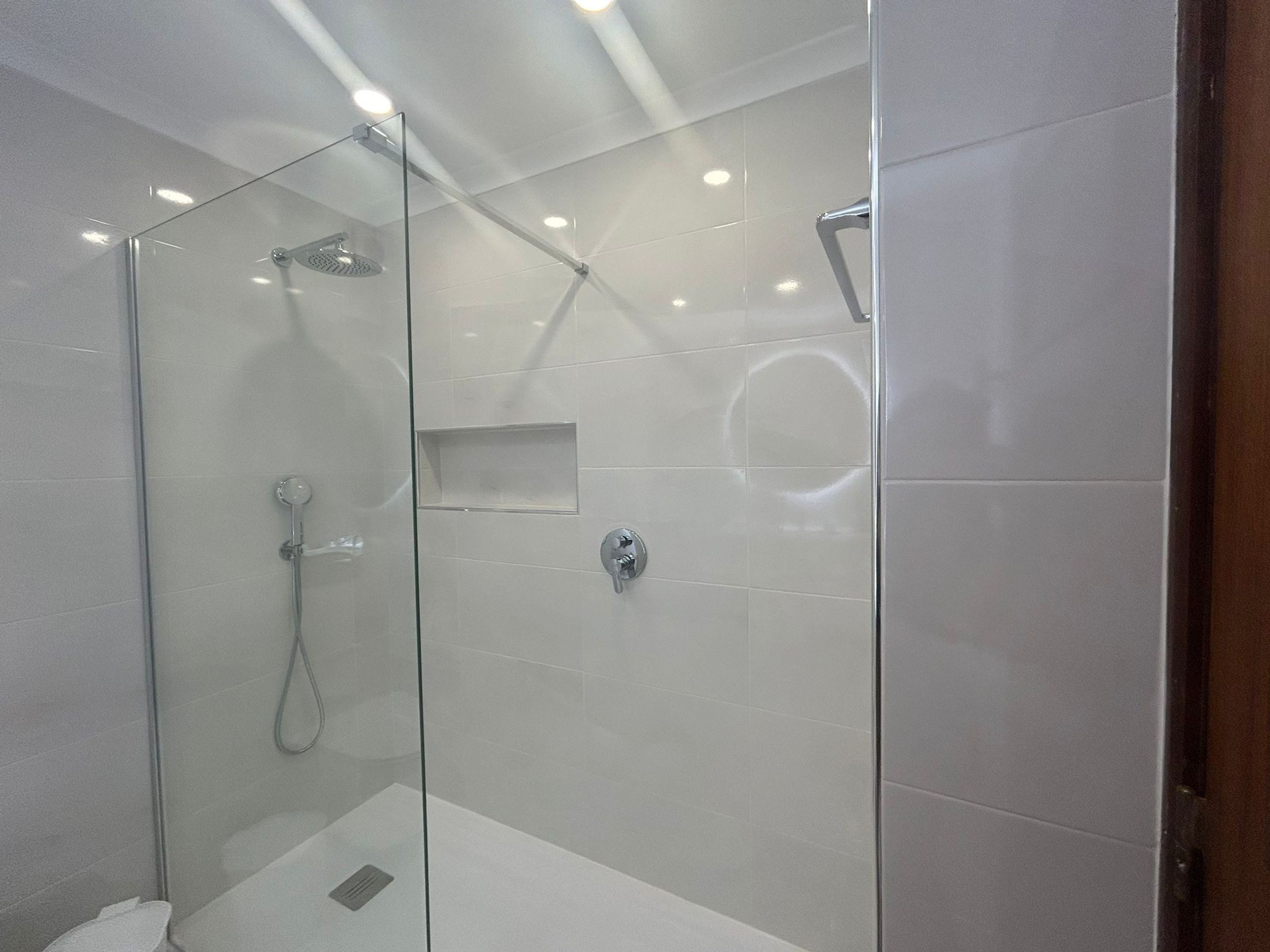 A modern shower with glass doors and a built-in shelf.