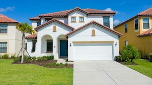 A two-story residential building with a white facade, red-tiled roof, and a garage. - Amazing House Verandapalms 6Bd With Pool (Kissimmee)