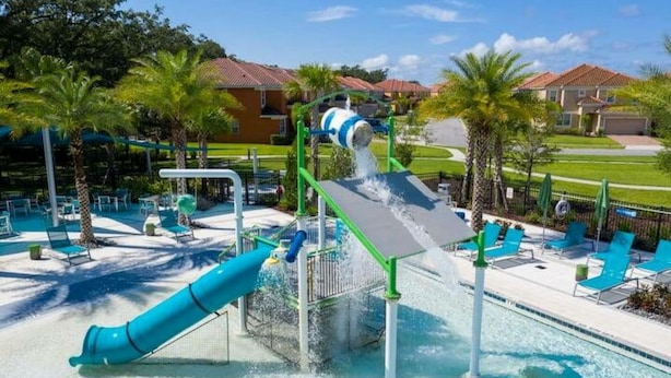 A water park with a water slide, pool, and lounge area with chairs and umbrellas. - Amazing House Verandapalms 6Bd With Pool (Kissimmee)