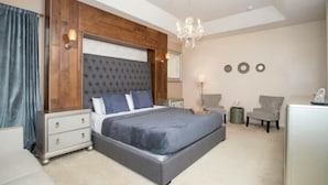 A bedroom with a large bed, a wooden headboard, a chandelier, a desk, and two chairs. - Amazing House Verandapalms 6Bd With Pool (Kissimmee)