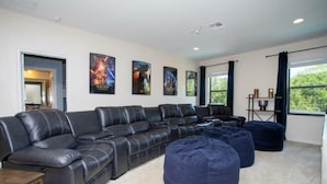 A modern living room with a sectional sofa, a coffee table, and a bean bag. There are framed posters on the wall and a window with curtains. - Amazing House Verandapalms 6Bd With Pool (Kissimmee)