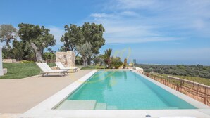 A rectangular pool with a stone border, surrounded by white lounge chairs and a stone wall. - TD Tenuta Donna Madia Sea View Pool Over Vineyard (Monopoli)