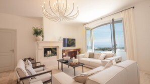 A spacious living room with a fireplace, comfortable seating, and a large window offering a view. - TD Tenuta Donna Madia Sea View Pool Over Vineyard (Monopoli)