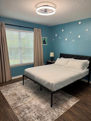 A bedroom with a bed, a nightstand, a window with curtains, a wall clock, and a ceiling fan. - 4 Minutes to Navarre Beach, Pet Friendly, Huge Yard (Navarre)
